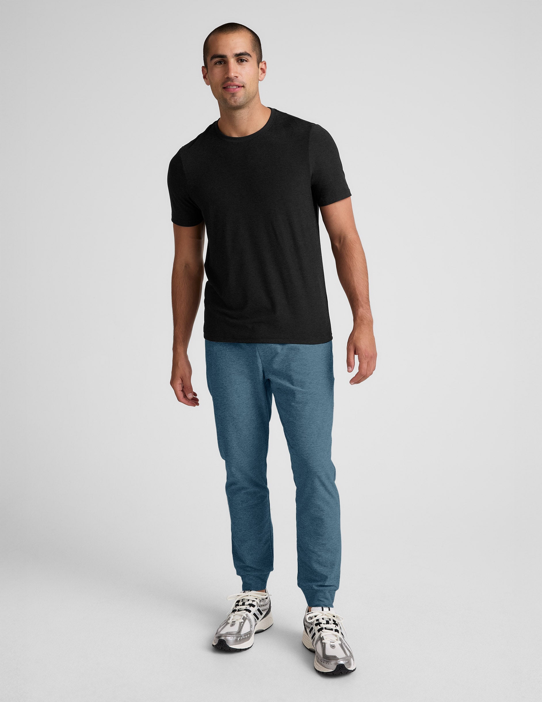 Man wearing Blue Spacedye™ Freefit Men's Jogger with banded cuffs, paired with a black t-shirt and silver sneakers.
