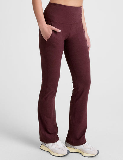 Woman wearing Maroon Spacedye™ High Waisted Practice Pocket Bootcut Pant with hands in pockets and cream sneakers.