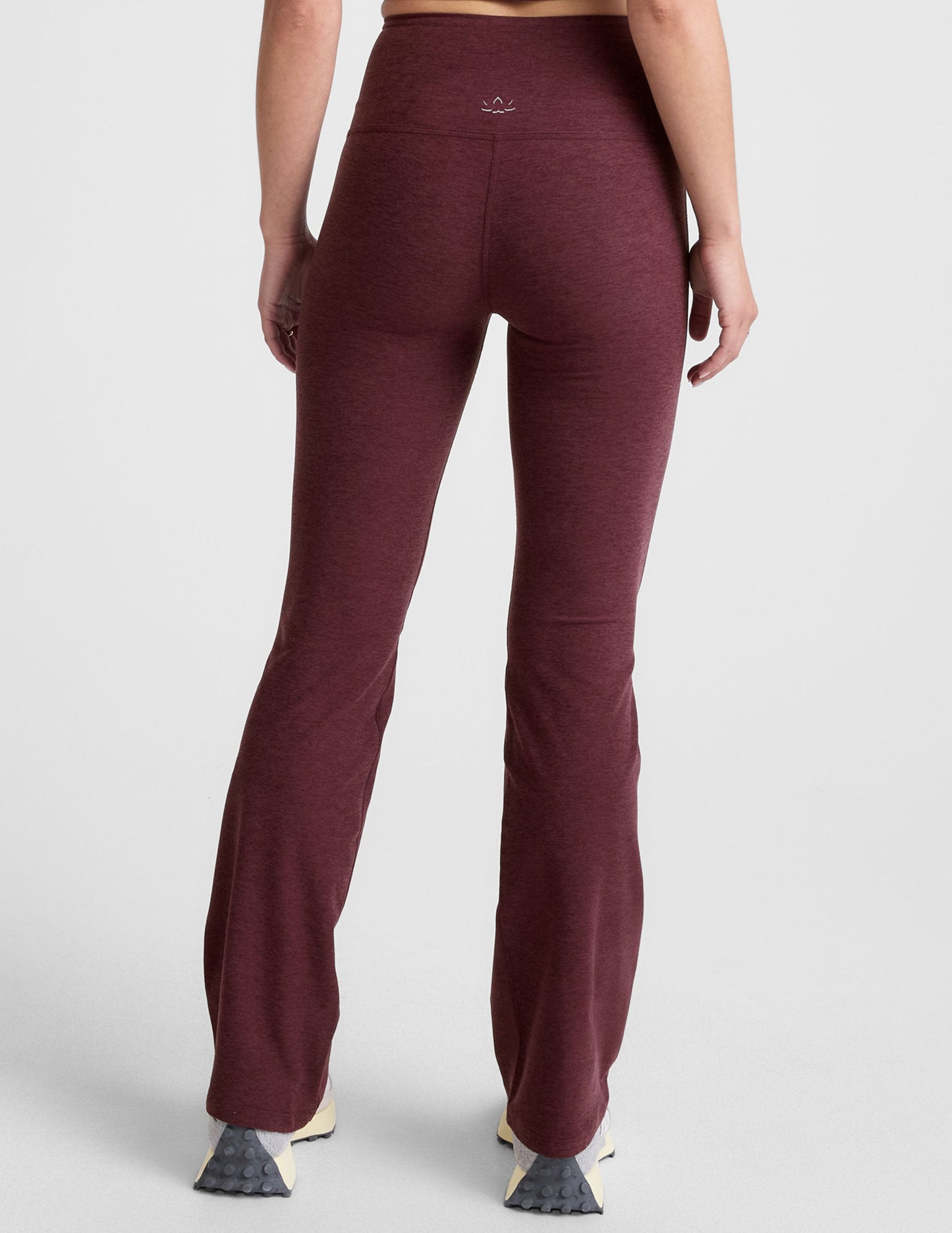 Woman wearing Maroon Spacedye High Waisted Practice Pocket Bootcut Pant, rear view, paired with cream sneakers.