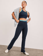 Navy Spacedye Layered Bootcut Pant featuring a teal double-layer waistband and flared hem on a model in white sneakers.