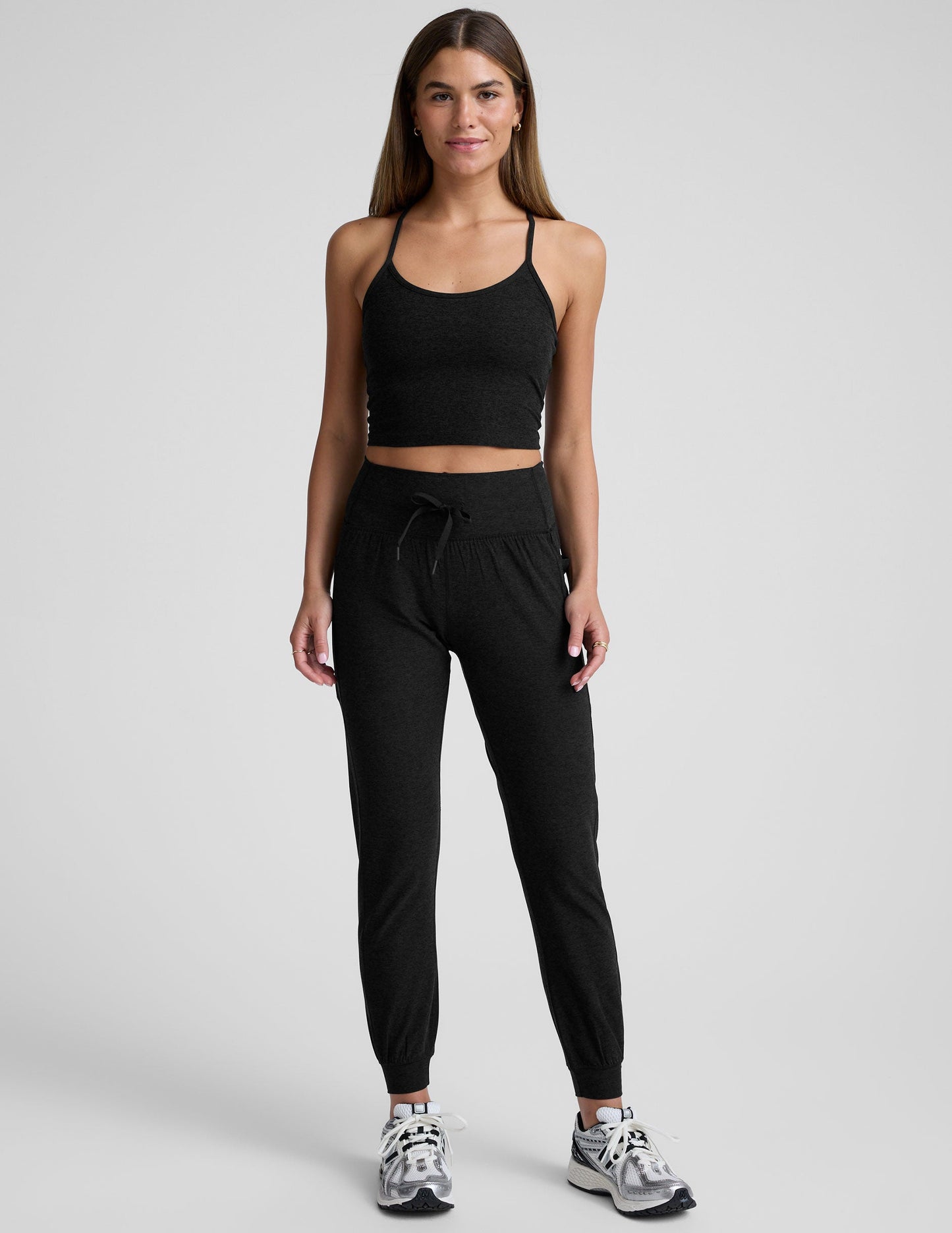 Woman wearing black Spacedye Go Pocket Jogger with high drawstring waist and cuffed ankles, standing against grey background.
