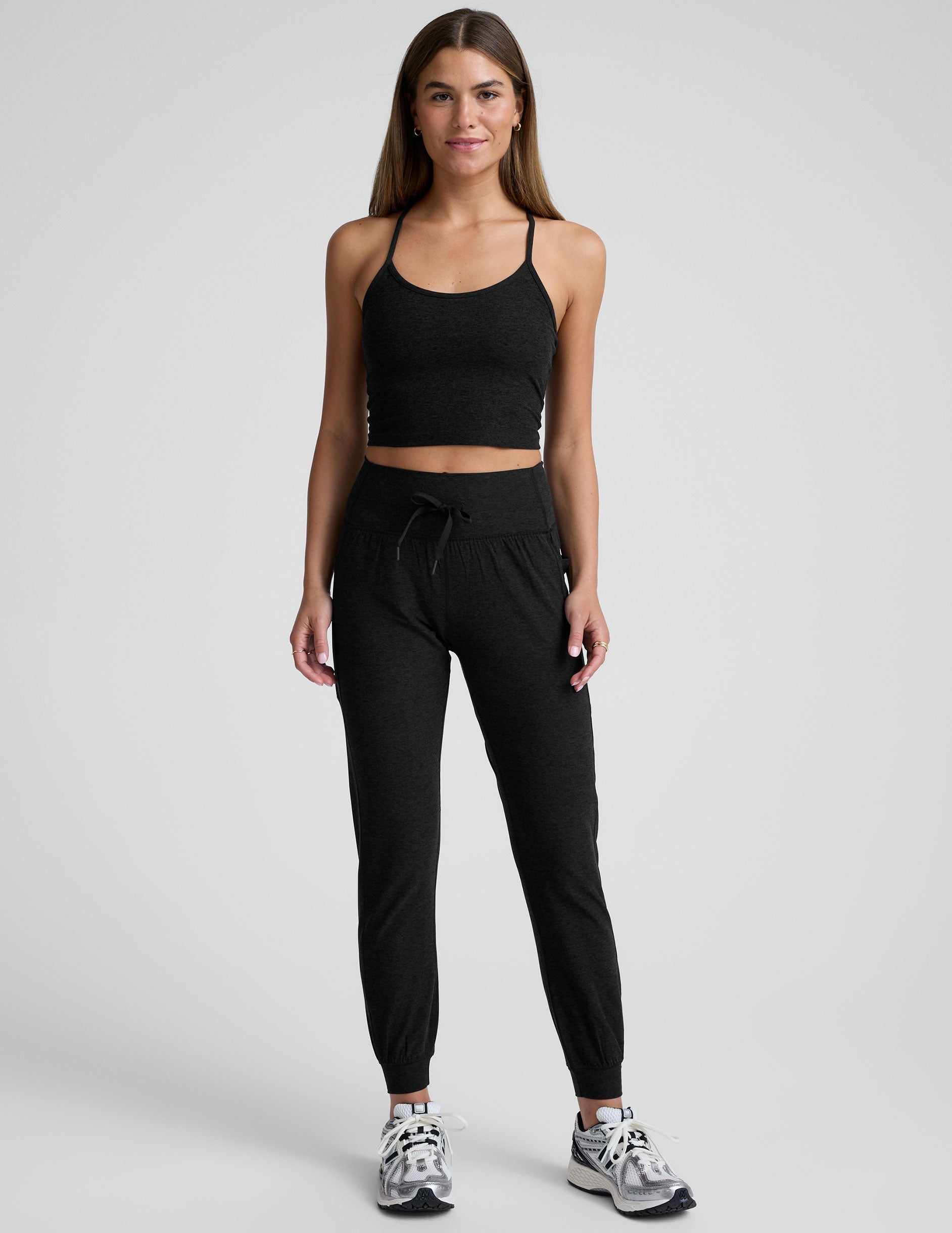 Woman wearing black Spacedye Go Pocket Jogger with high drawstring waist and cuffed ankles, standing against grey background.