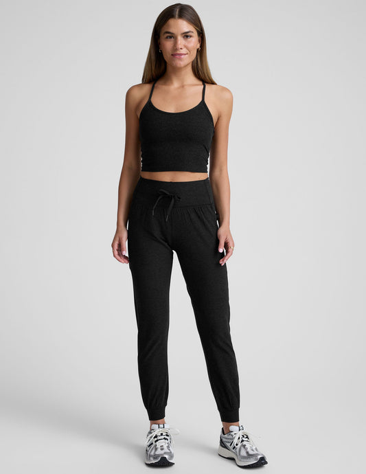 Woman wearing black Spacedye Go Pocket Jogger with high drawstring waist and cuffed ankles, standing against grey background.