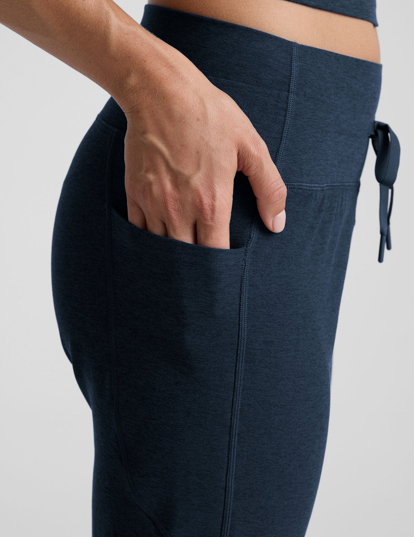 Close-up of a hand in the pocket of navy Spacedye Go Pocket Joggers showing the high waistband and drawstring detail.