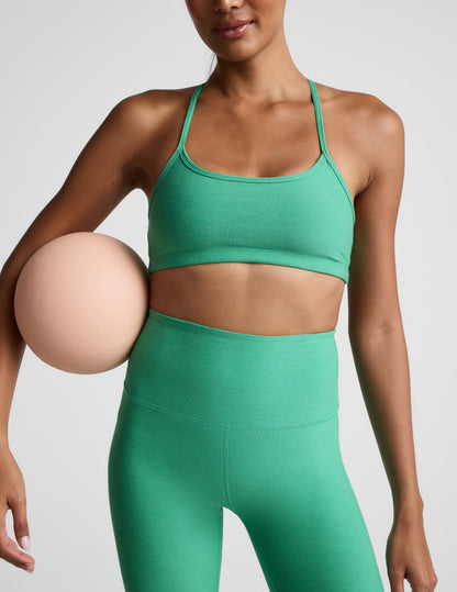 Woman wearing a green bra and green high-waisted midi leggings against a plain background.