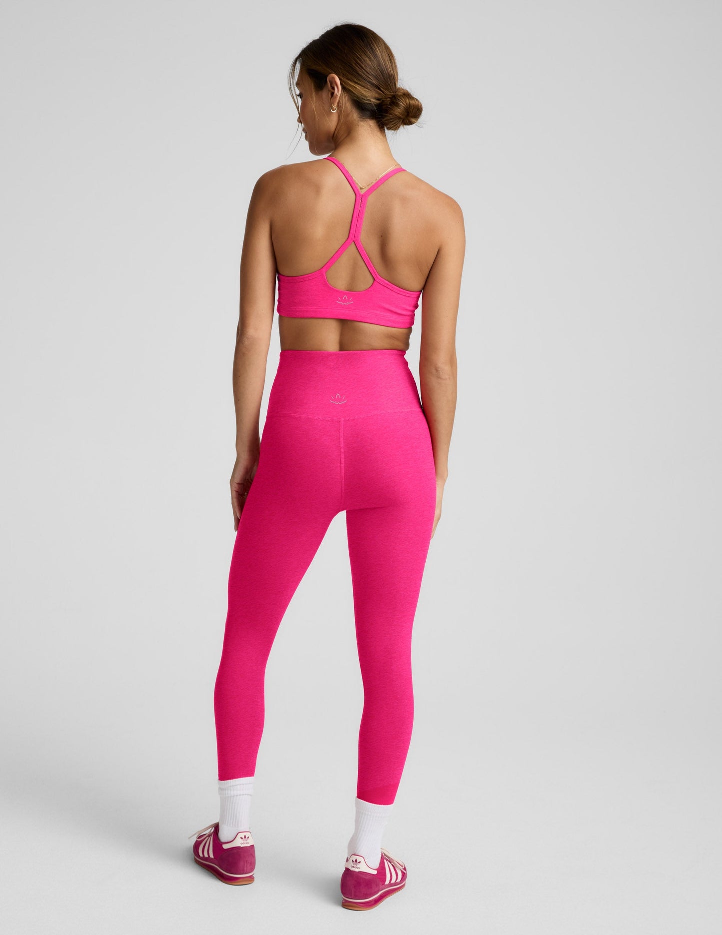 Woman wearing a pink bra and leggings against a plain background.