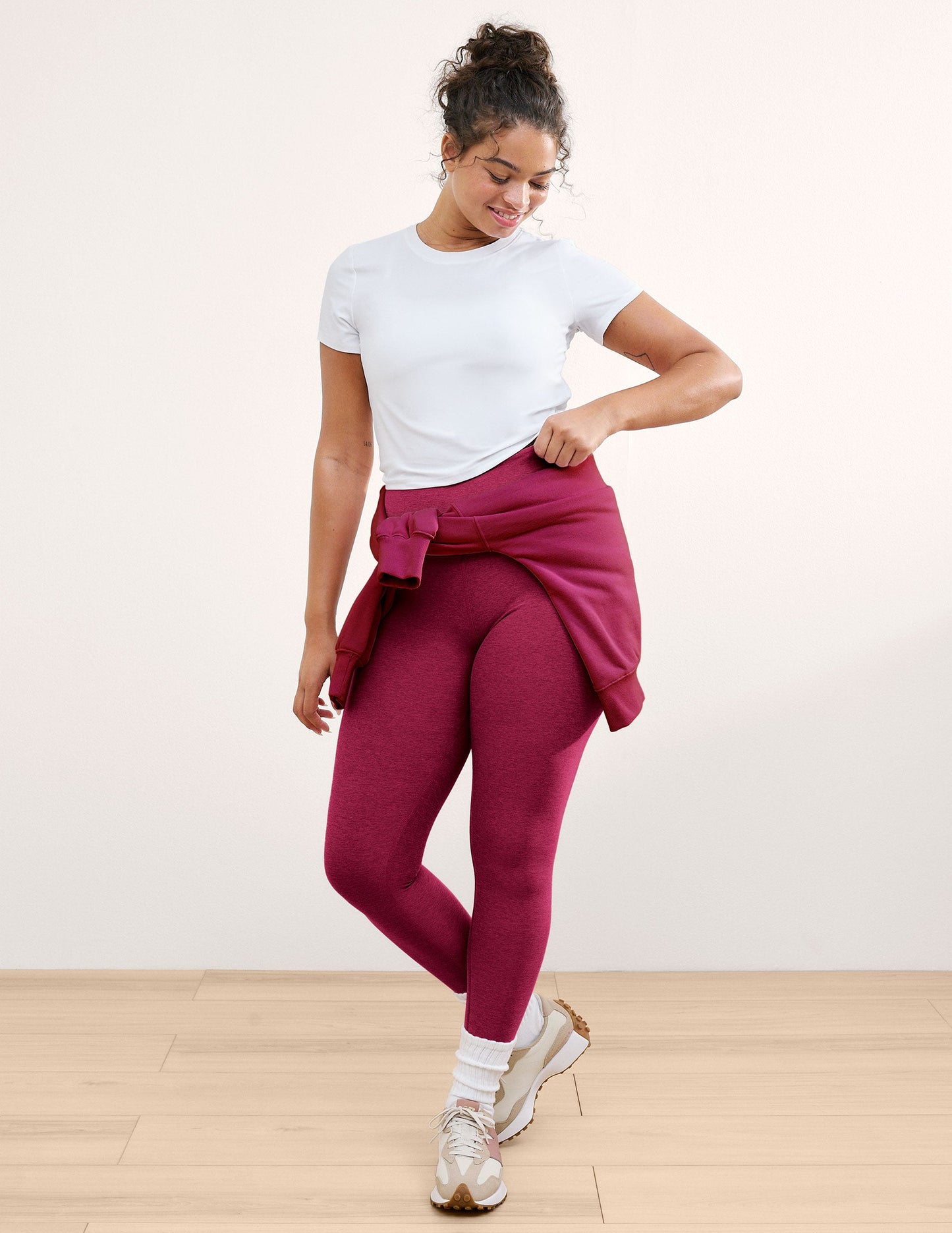 Woman wearing a white t-shirt and leggings against a plain background.