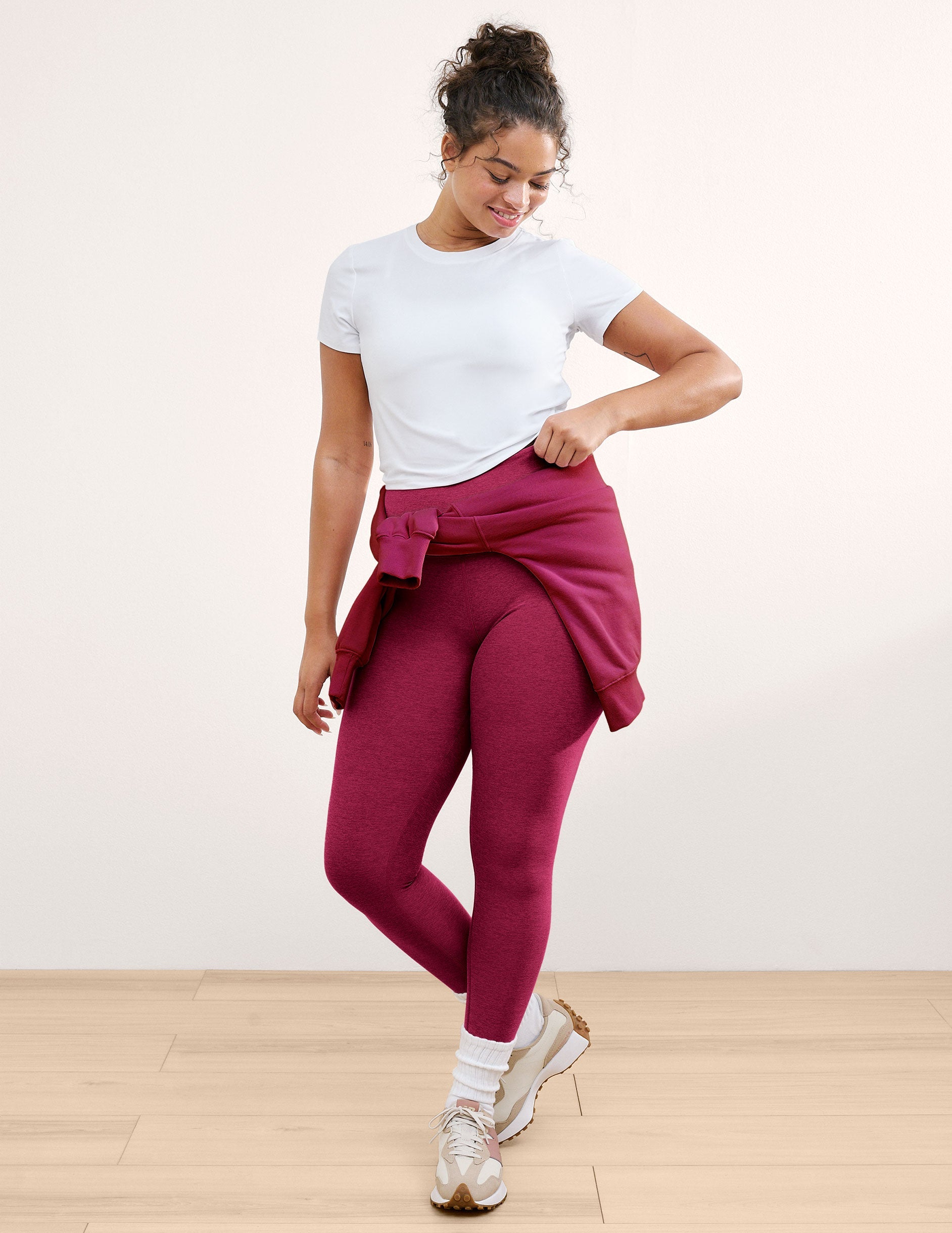 Woman wearing a white t-shirt and leggings against a plain background.