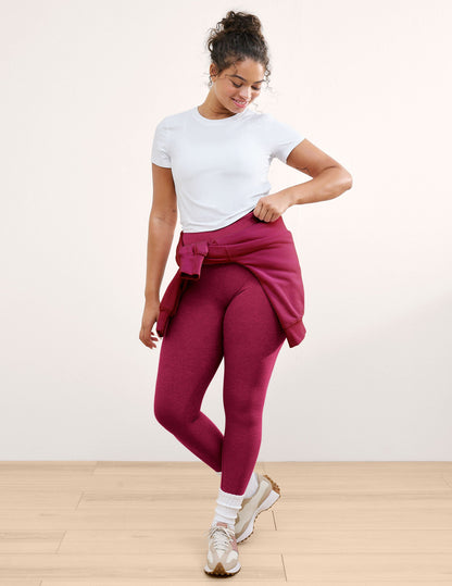 Woman wearing a white t-shirt and leggings against a plain background.