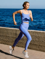 Woman running by the ocean wearing a matching blue set.
