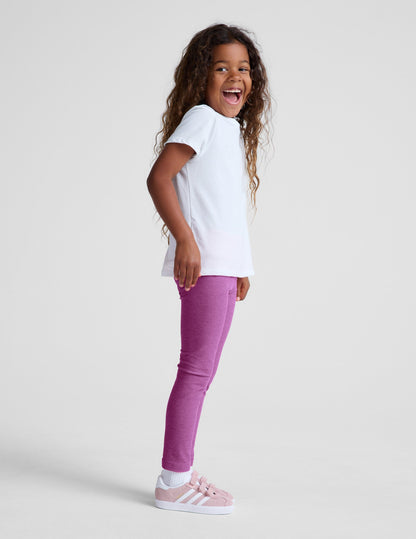Girl wearing Purple Spacedye Toddler Legging paired with a white t-shirt and pink sneakers.