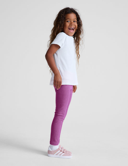 Girl wearing Purple Spacedye Toddler Legging paired with a white t-shirt and pink sneakers.