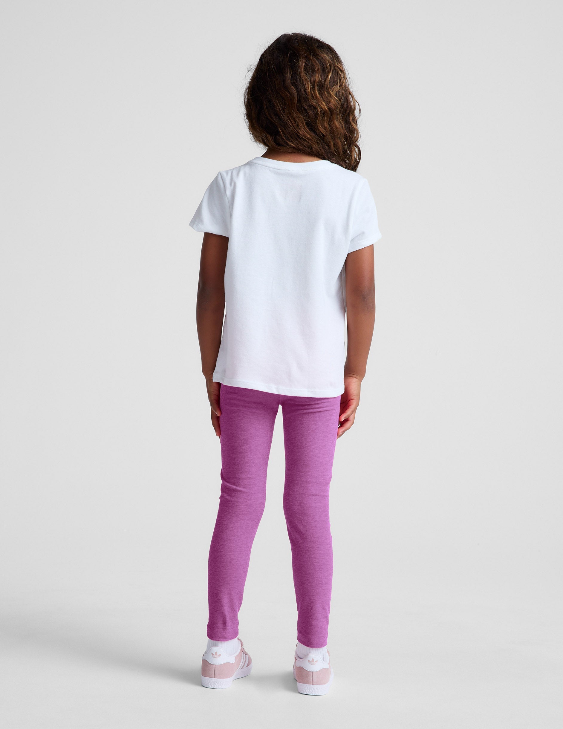 Rear view of girl wearing purple Spacedye Toddler Legging™ paired with a white t-shirt and pink sneakers.