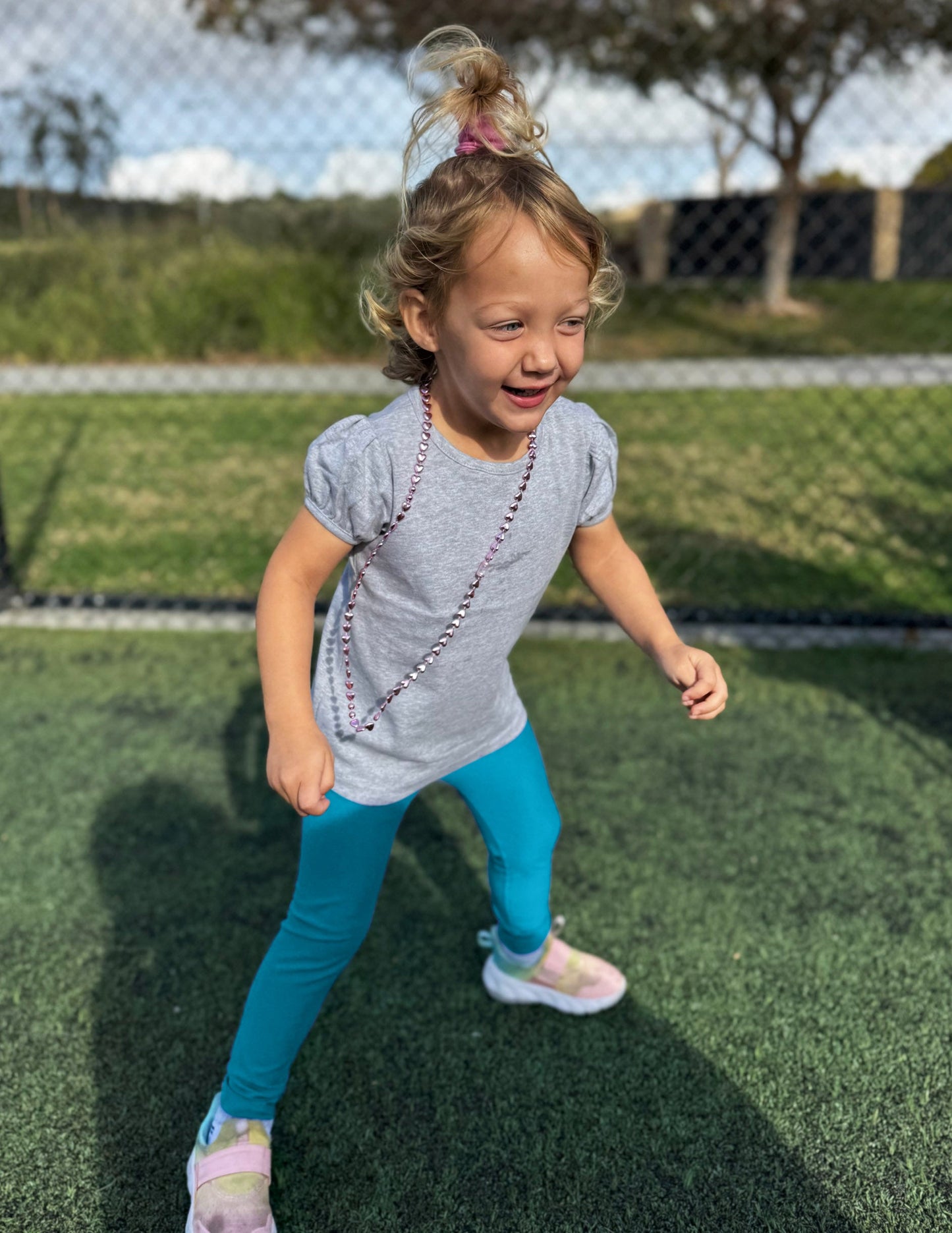 Girl wearing Blue Spacedye Toddler Legging™ paired with a grey puff-sleeve shirt and sneakers while playing.
