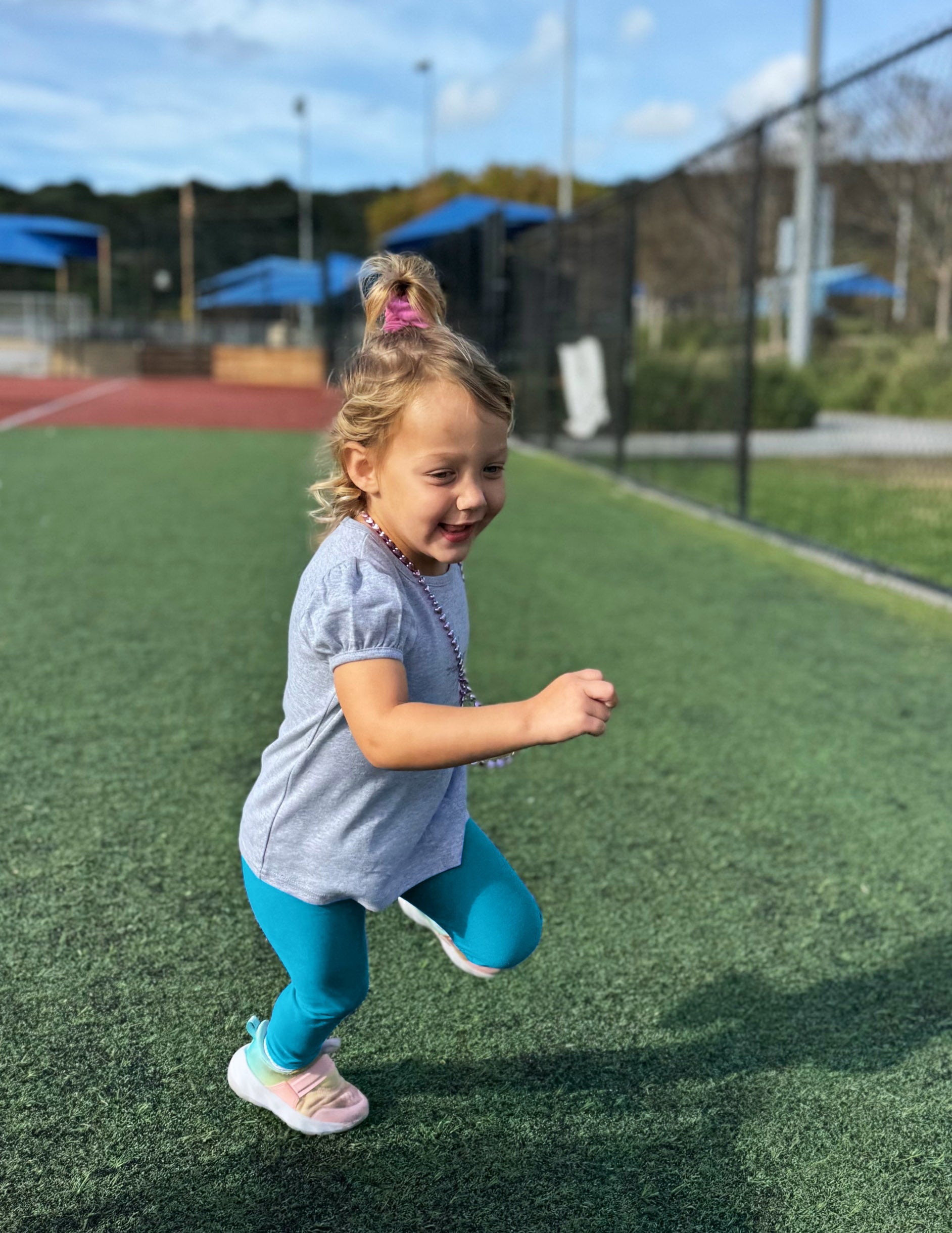 Toddler girl running in Blue Spacedye Toddler Legging™ paired with a grey puff-sleeve shirt and colorful sneakers.