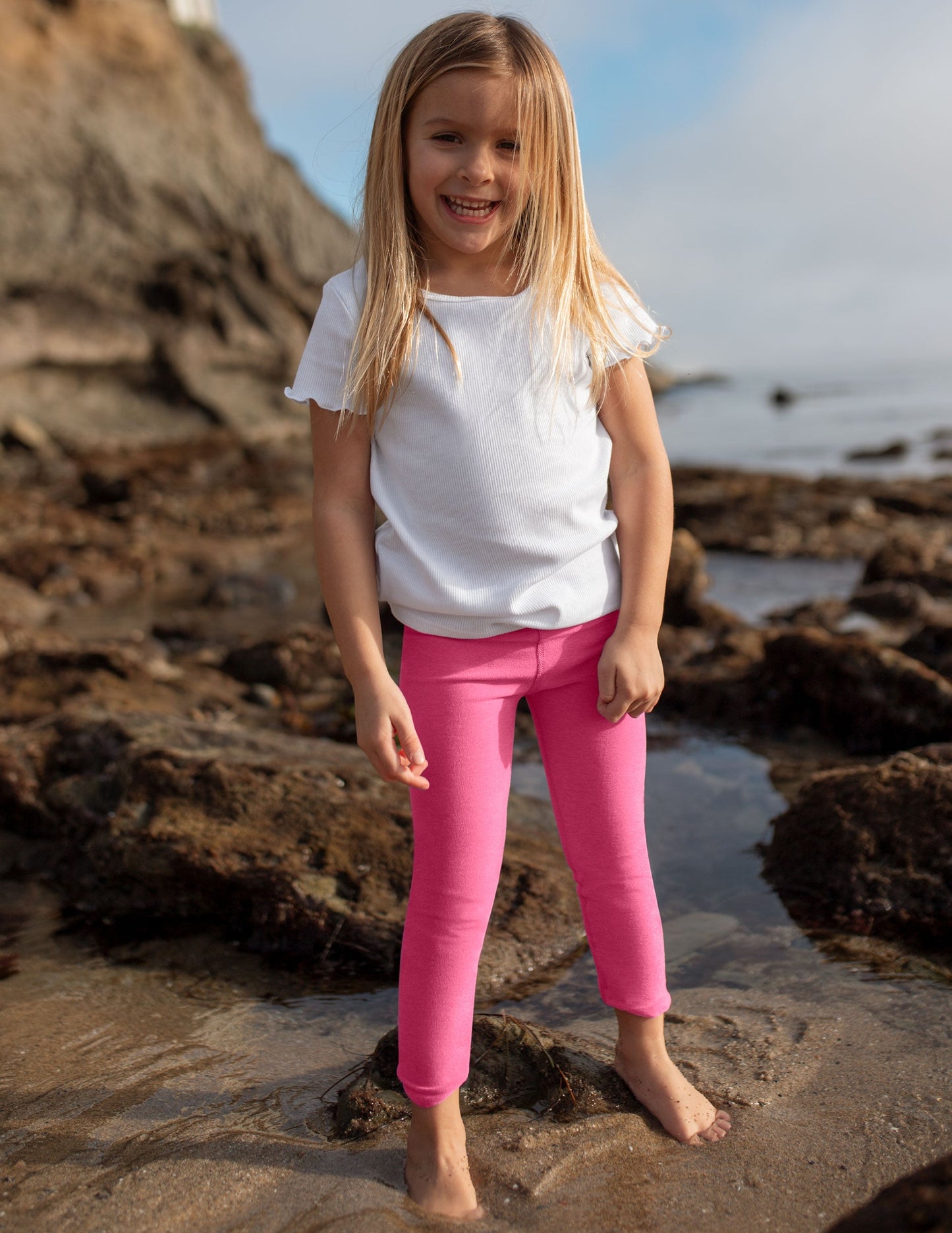 Girl wearing Pink Spacedye™ Toddler Legging with a high waistband paired with a white t-shirt.