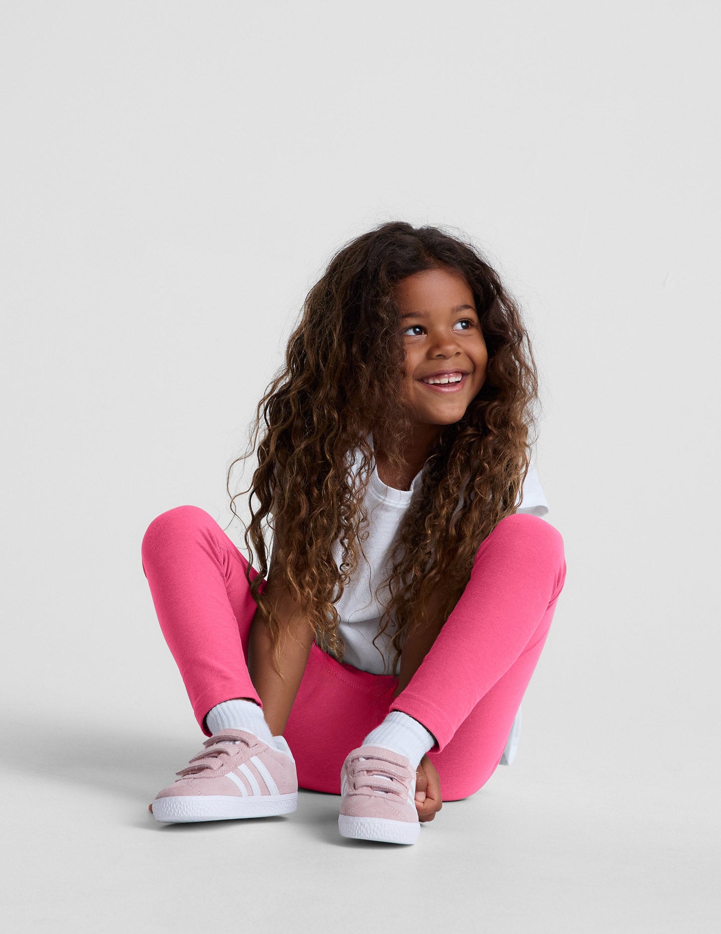 Girl wearing Pink Spacedye™ Toddler Legging paired with a white t-shirt and pink sneakers.