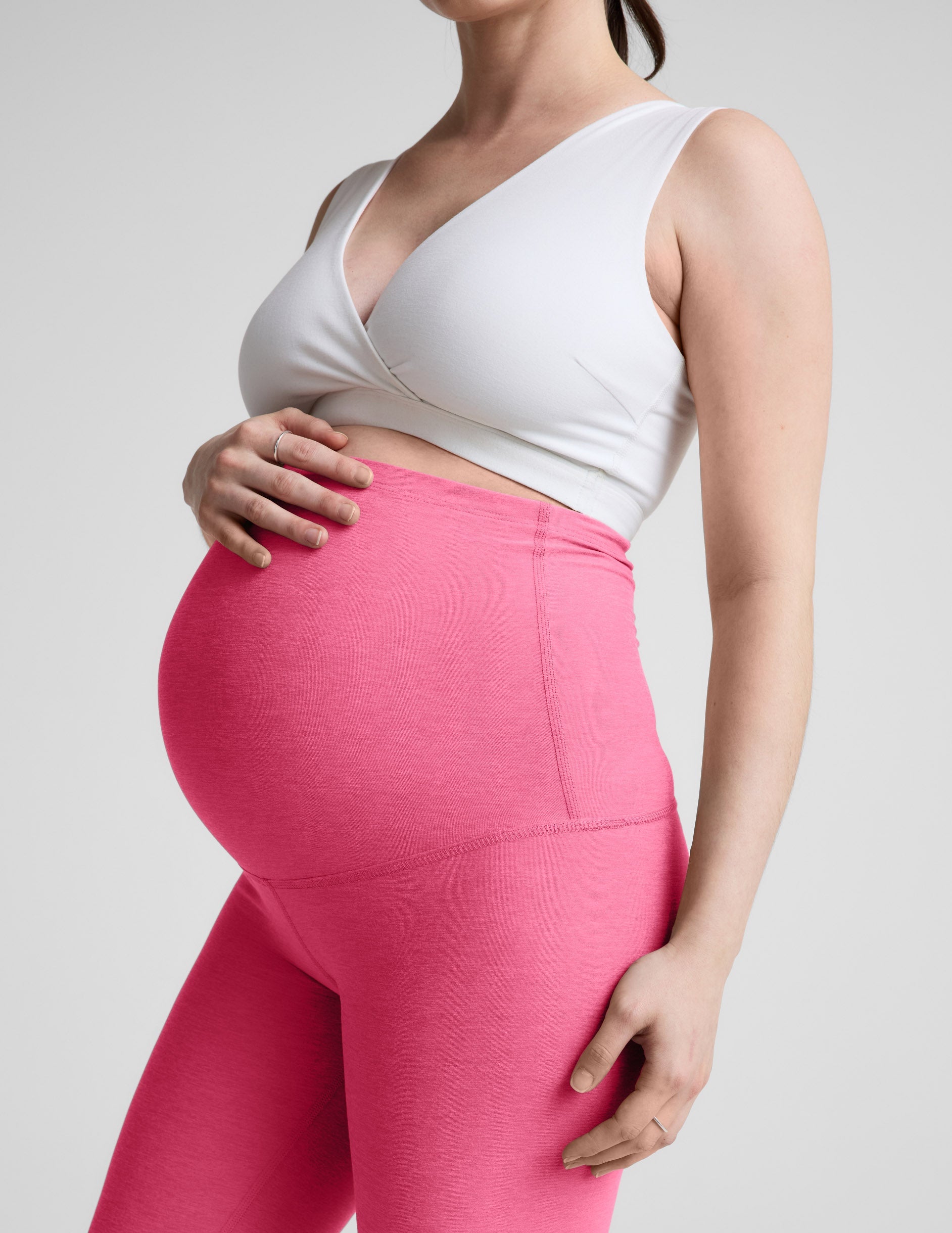 Woman wearing a white maternity bra and leggings against a plain background.