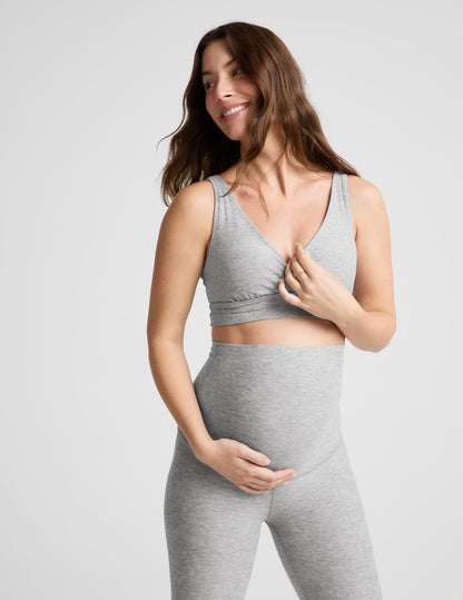 Pregnant woman wearing a gray bra and leggings on a plain background.