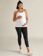 Pregnant woman wearing black marled Spacedye Love The Bump Capri Maternity Leggings and a white tank top, smiling.