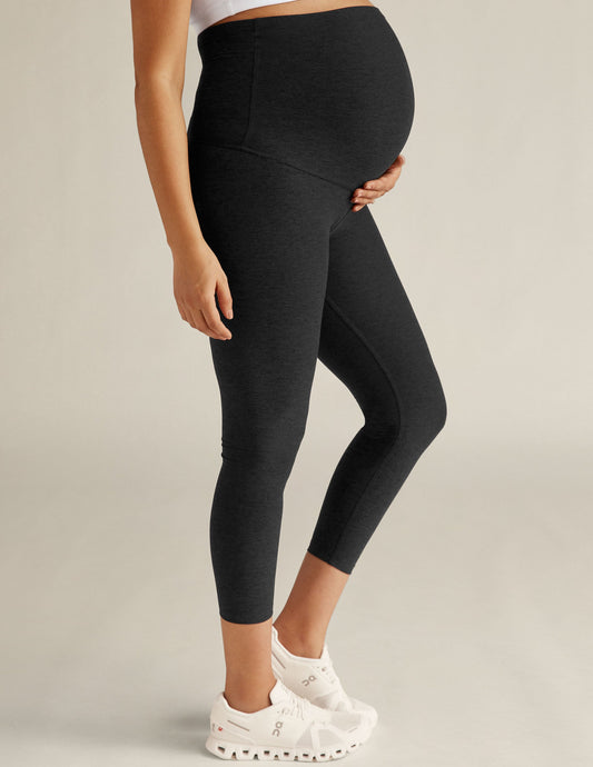 Pregnant woman wearing Spacedye Love The Bump Capri Maternity Leggings in marled black with high over-the-belly waistband.