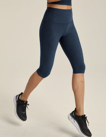 Spacedye Pedal Pusher High Waisted Legging in navy marled fabric on a model mid-stride wearing black running shoes.