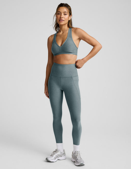 Woman wearing a gray bra and leggings against a plain background.