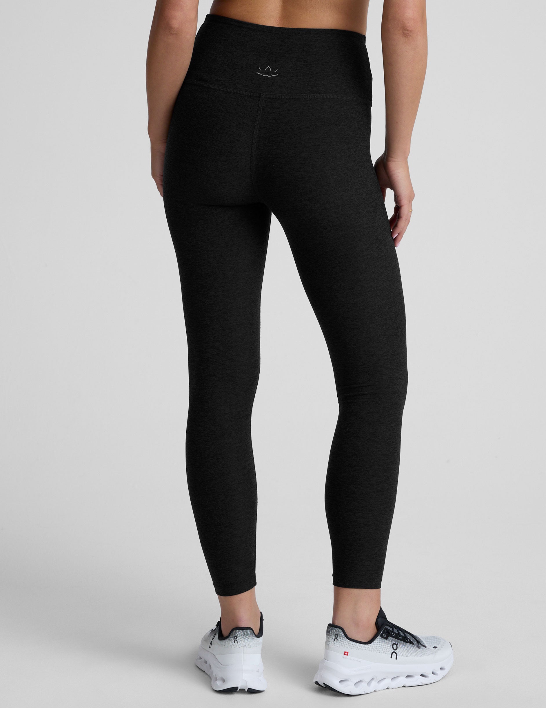 Black leggings with a front crossover waistband worn by a person on a light gray background.