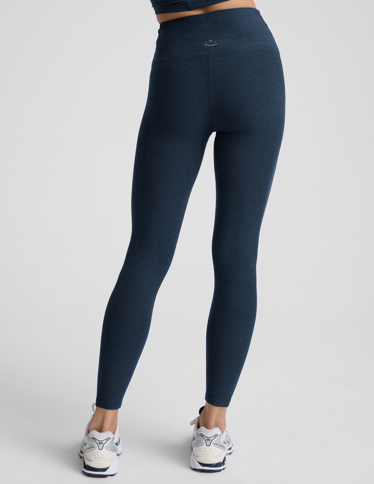 Person wearing navy blue leggings with a front crossover waistband on a plain background.