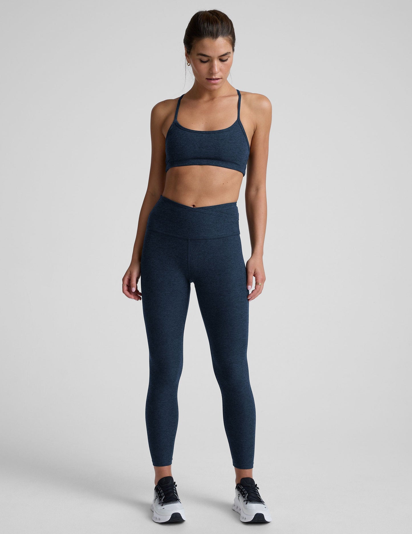 Woman wearing a navy athletic outfit on a light gray background