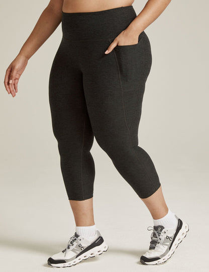 Side view of Spacedye Out Of Pocket High Waisted Capri Legging in dark gray marled fabric with hand in side pocket.