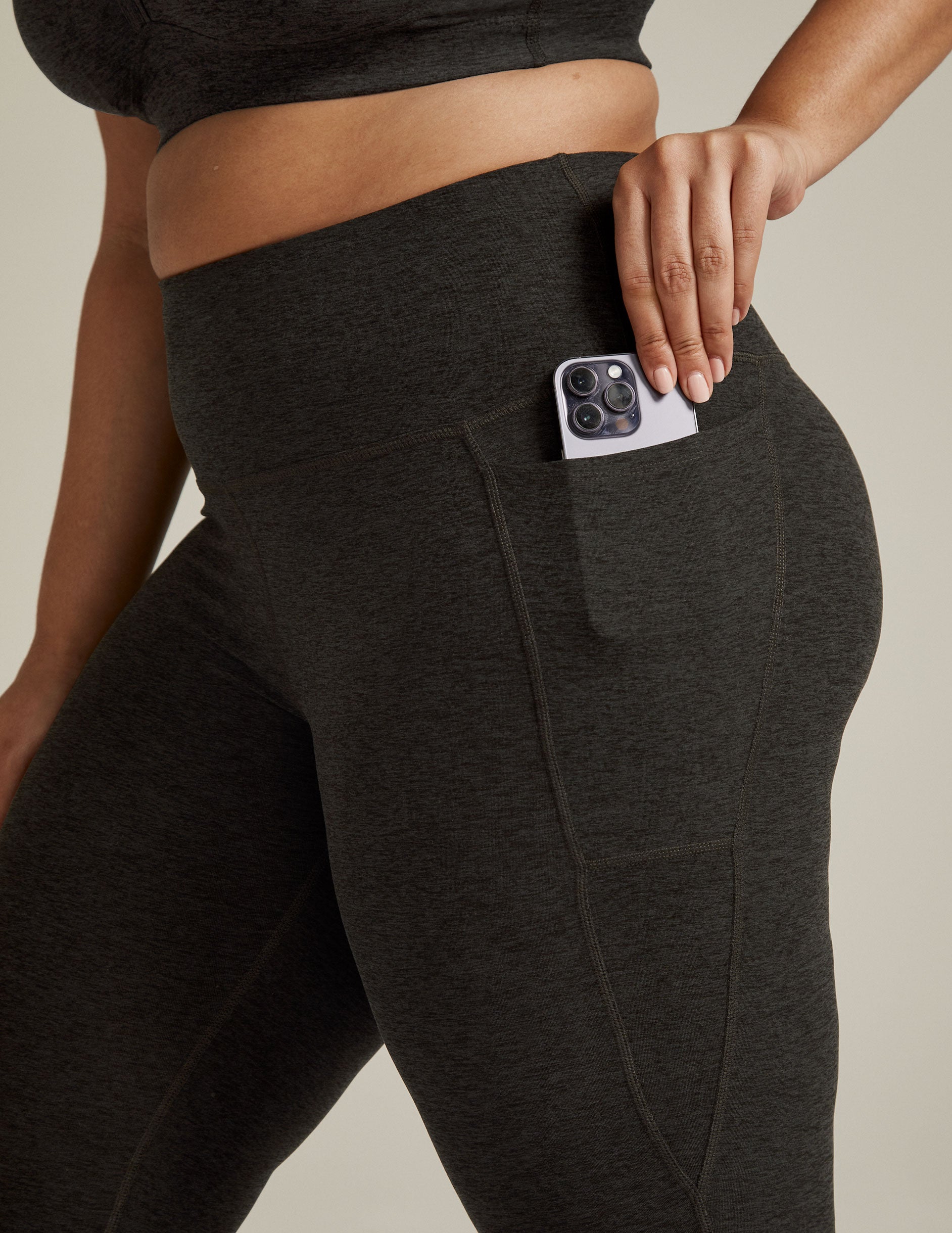 Spacedye Out Of Pocket High Waisted Capri Legging in marled dark gray with a phone tucked into the side hip pocket.