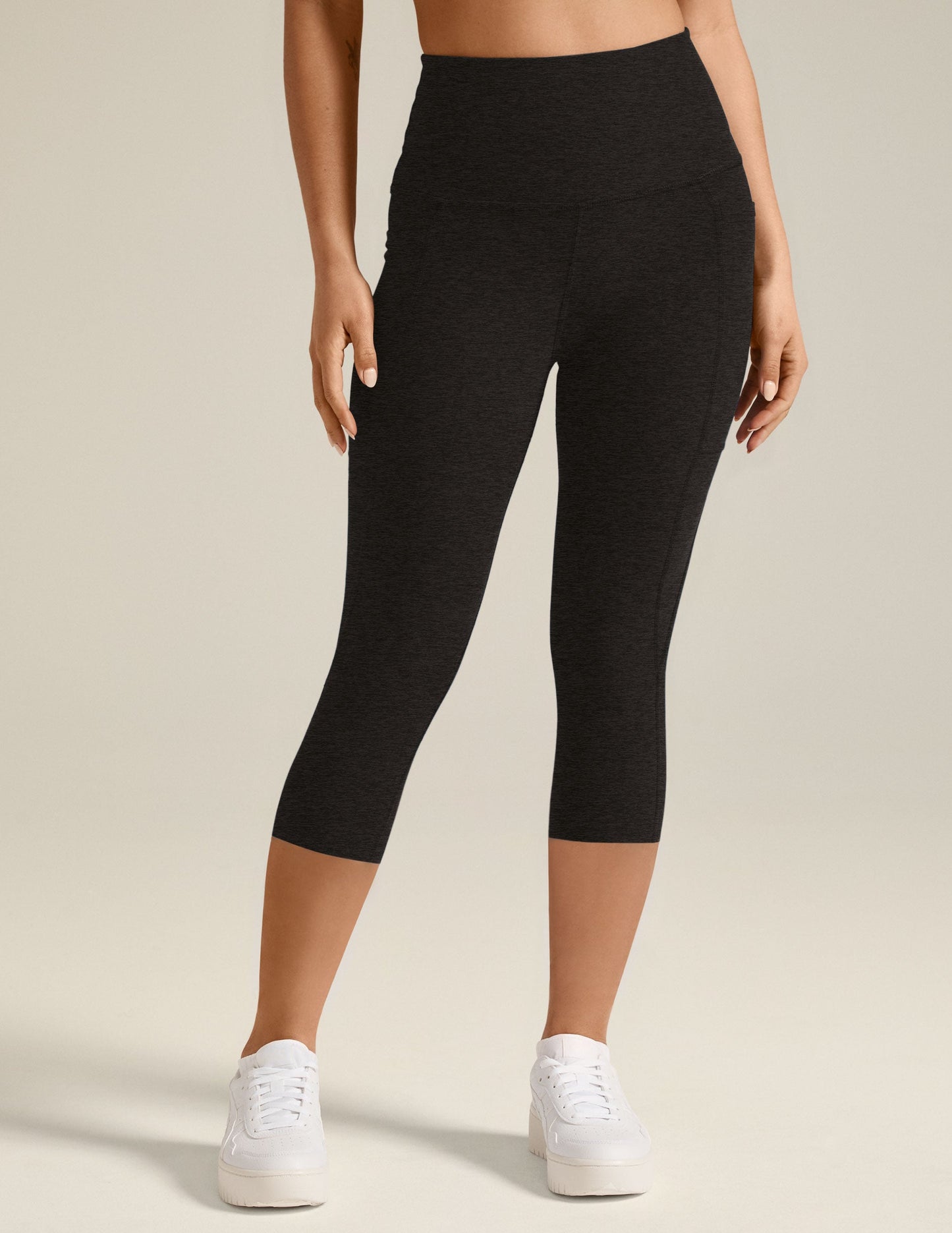 Black marled Spacedye Out Of Pocket High Waisted Capri Legging on a model with side pockets and white sneakers.