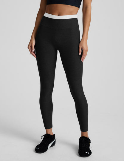 Person wearing black leggings and black athletic shoes on a light gray background.