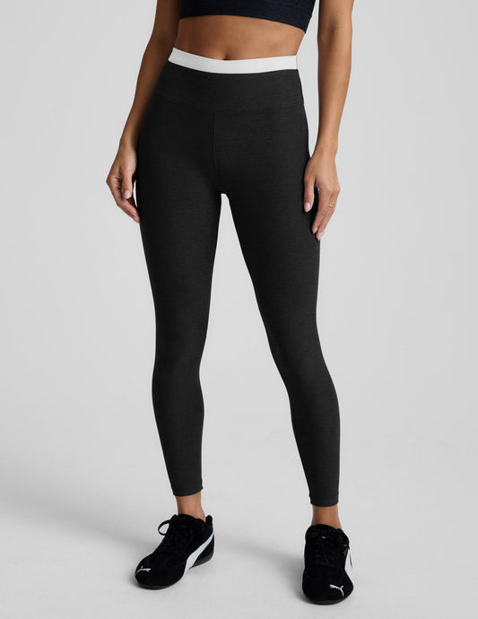 Person wearing black leggings and black athletic shoes on a light gray background.