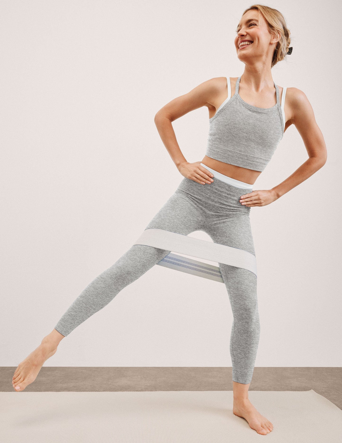 Woman in gray athletic outfit posing against a plain background.