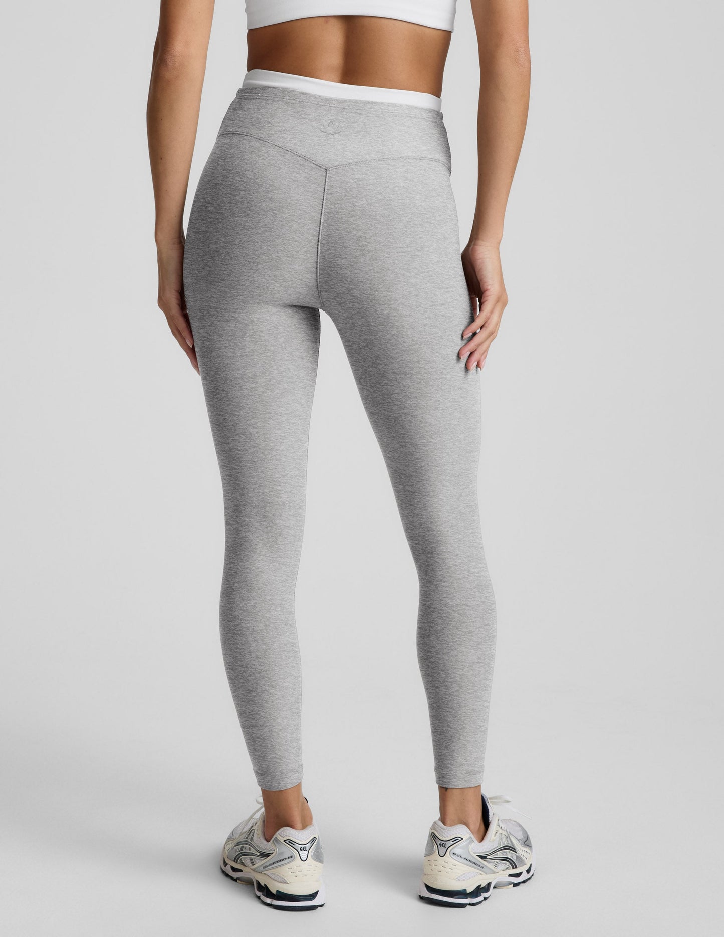 Person wearing gray leggings on a plain background.
