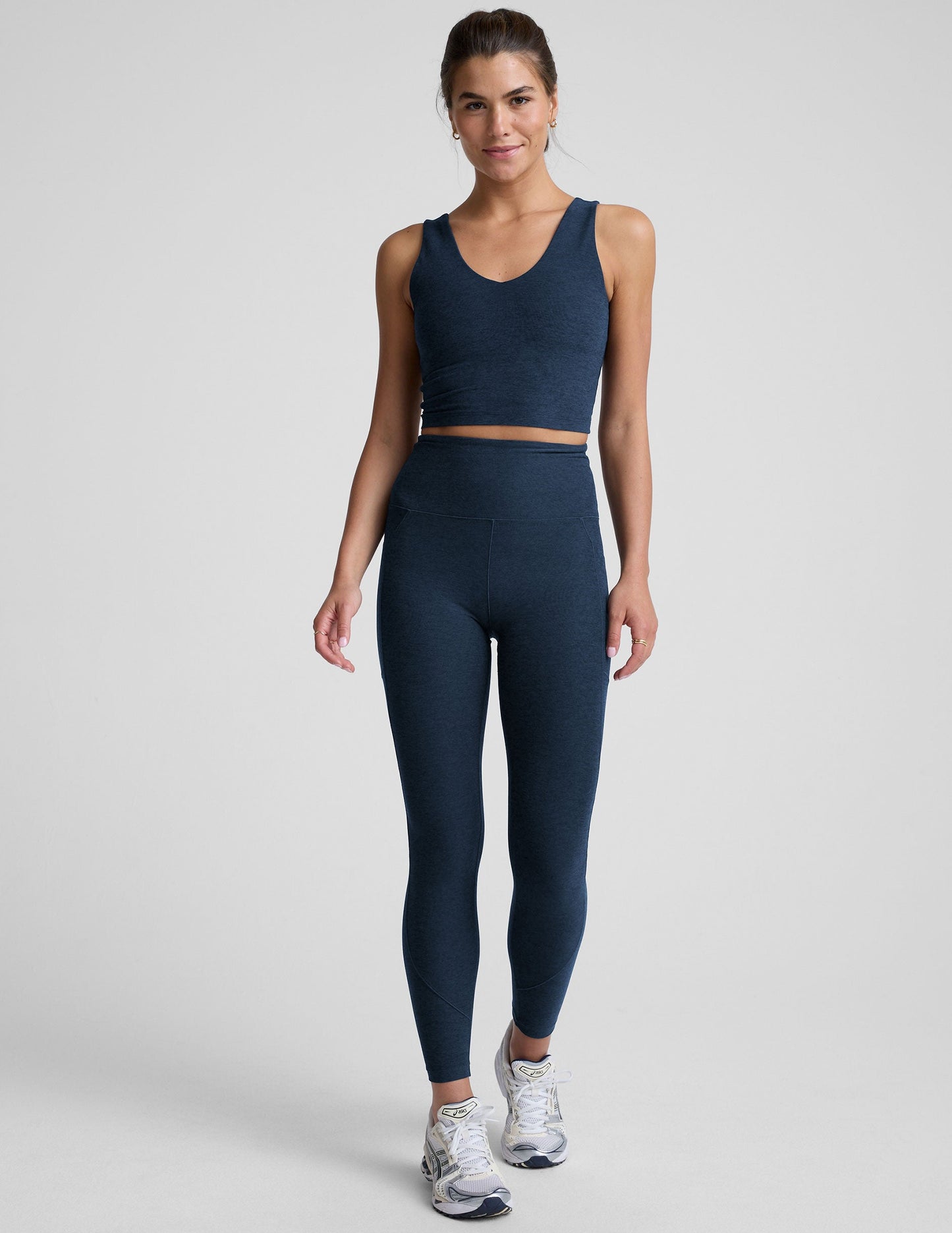 model wearing blue midi length leggings with 3 pockets against a plain background.