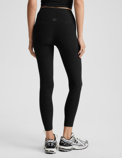 Woman wearing black midi length leggings against a plain background.