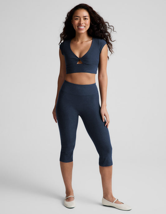 Smiling model wears navy Spacedye Mid-Rise Slit Pedal Pusher Legging featuring a wide waistband and mid-calf cropped length.