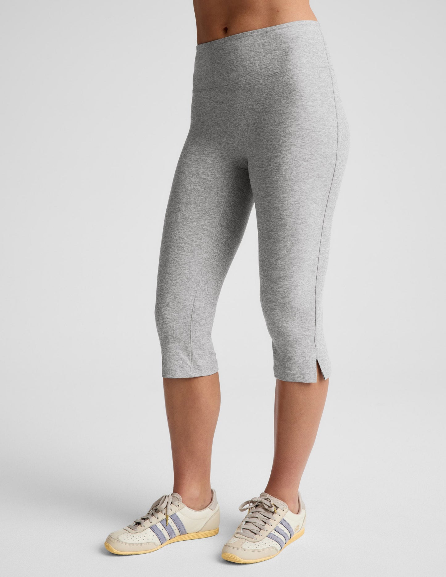 Side view of grey marled Spacedye Mid-Rise Slit Pedal Pusher Legging with side slits at the hem, worn with sneakers.