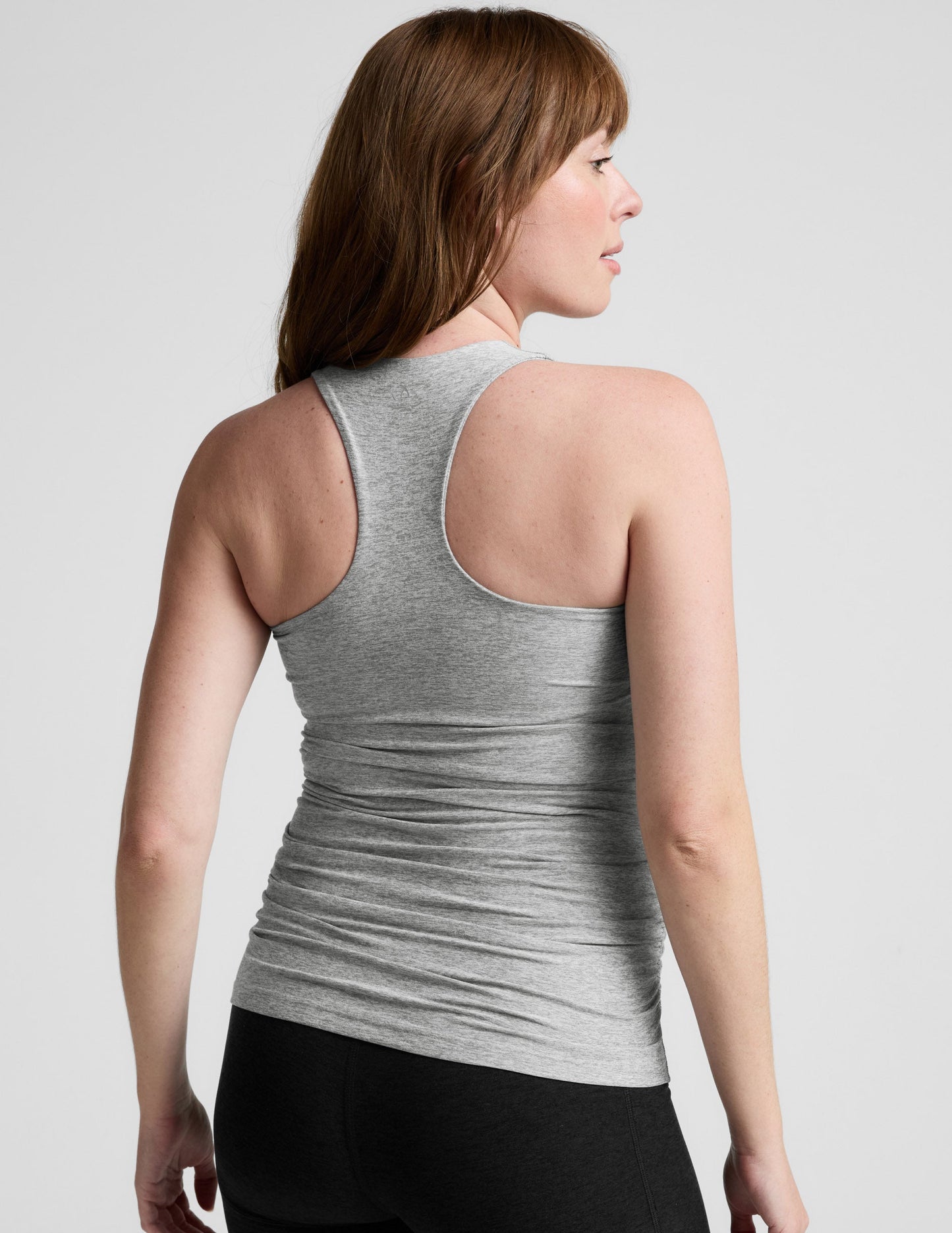 Woman wearing a gray maternity tank top and black shorts on a white background.