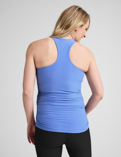 Pregnant woman wearing a blue tank top and black shorts on a white background.