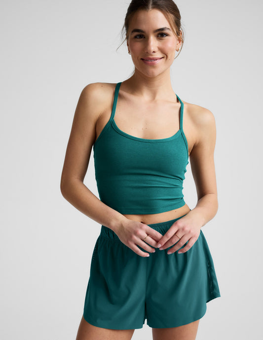 Woman wearing a green cropped tank and shorts against a plain background.
