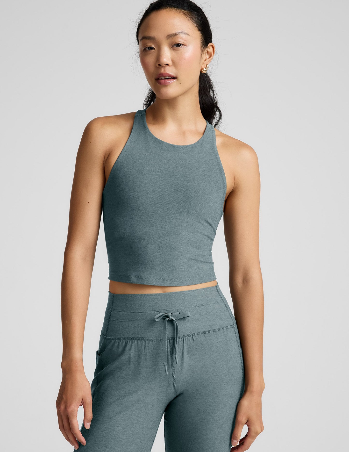 Woman wearing a green athletic outfit on a light gray background.