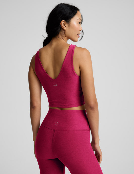 Woman wearing a red cropped v-neck tank and leggings against a plain background.