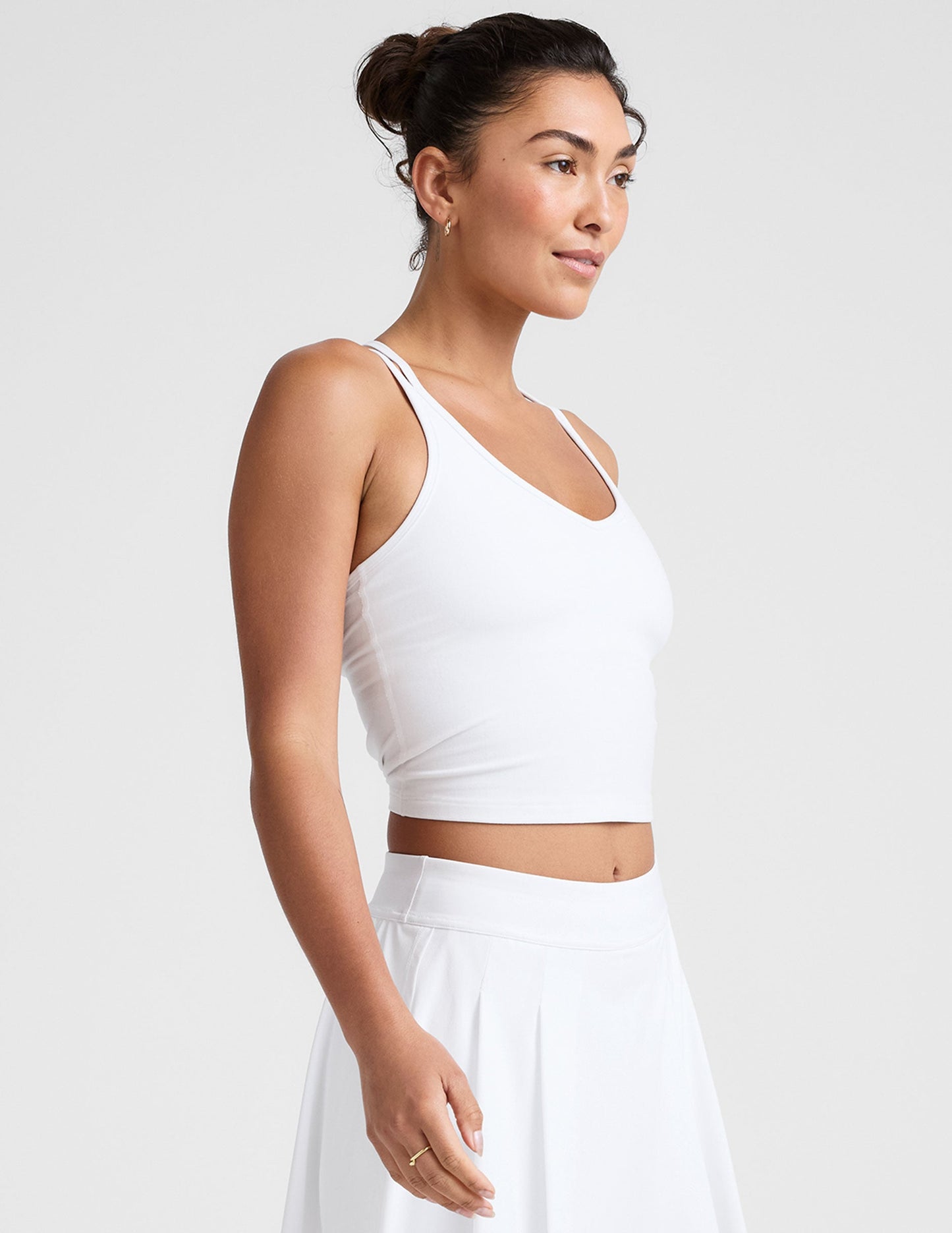 white waist length, V neckline​ tank top with a self shelf bra and criss-cross strap back detail​.