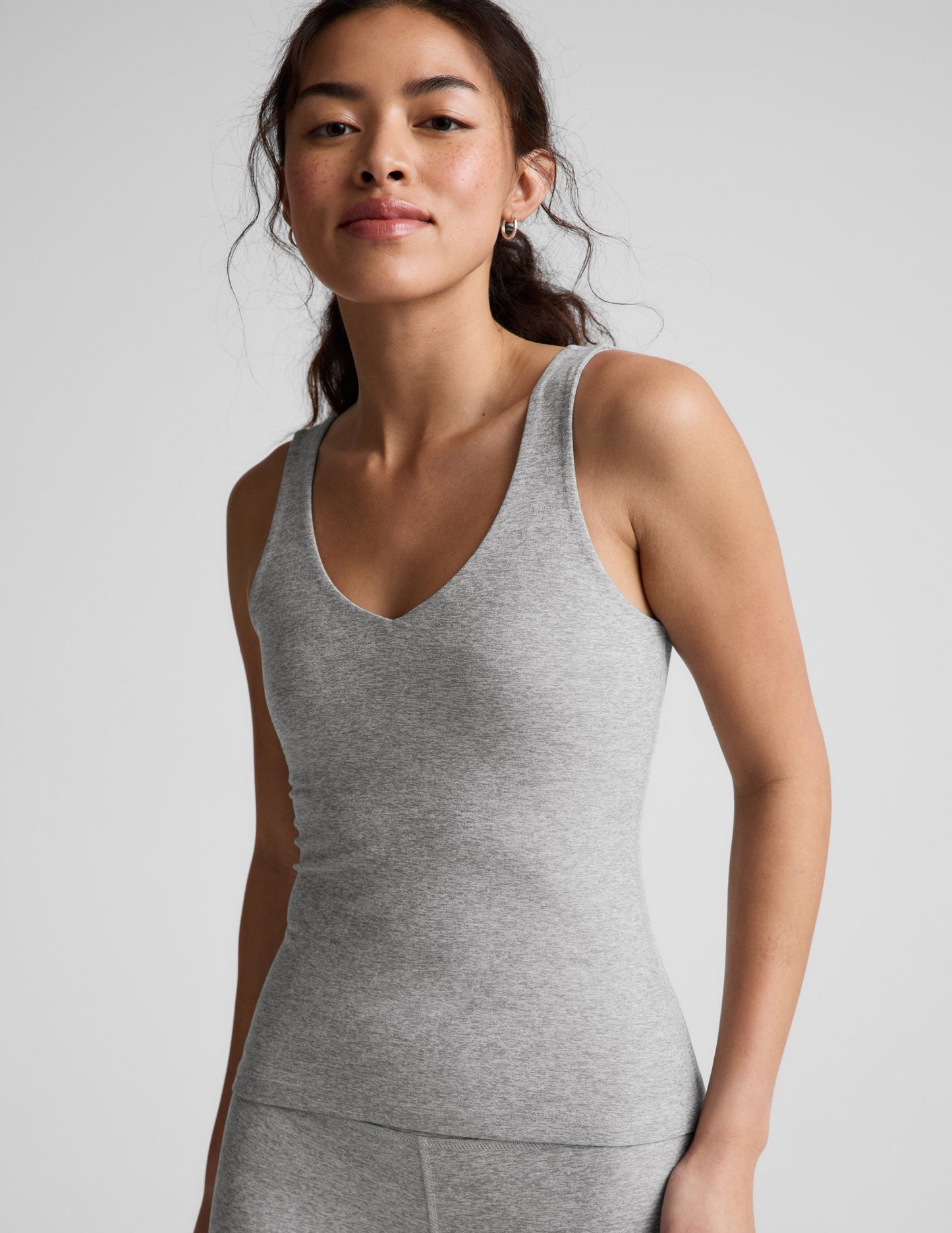 Woman wearing a gray tank top against a plain background.