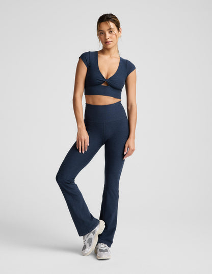 Woman wearing a navy blue cropped twist tee and pants on a light gray background.