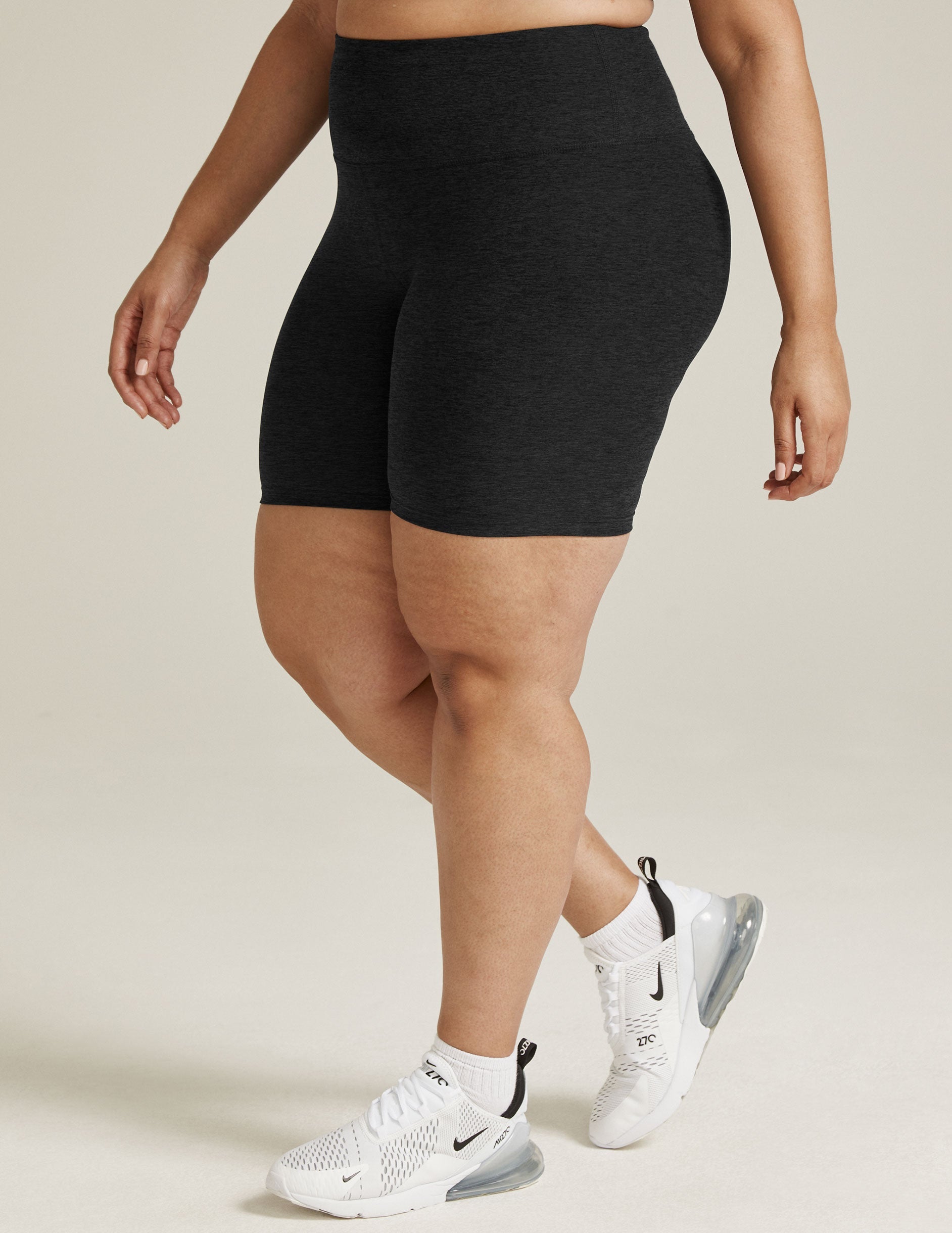 Model in black Spacedye High Waisted 7" Biker Shorts and white sneakers, shown from the waist down in a side-profile stance.